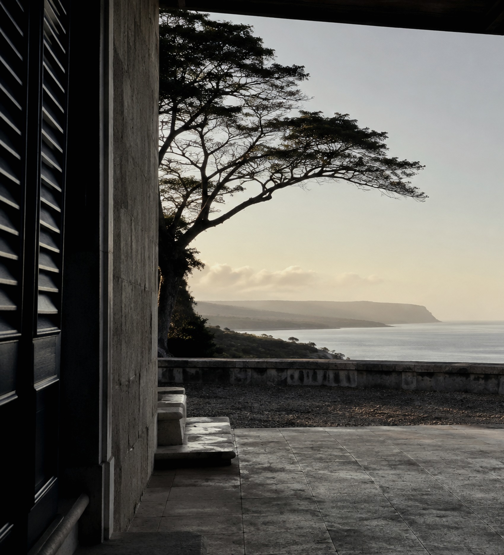 Editorial study of stone, shutters, tree canopy and an Indian Ocean horizon.